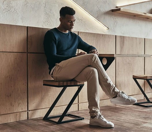 Un homme assis sur une chaise en bois regardant son téléphone.