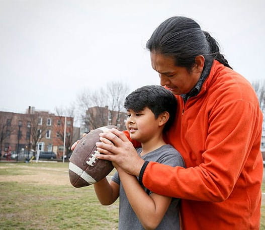 Un père apprend à son fils à lancer un ballon de football