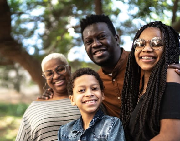 Trois adultes et un enfant souriant dehors